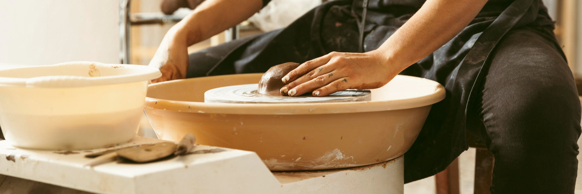 Person working with clay on a pottery wheel in a workshop setting