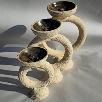 Ceramic tiered plant stand with three round bowls on a gray background