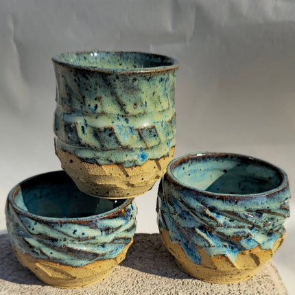 Three ceramic pots with textured blue and brown glaze on a neutral background