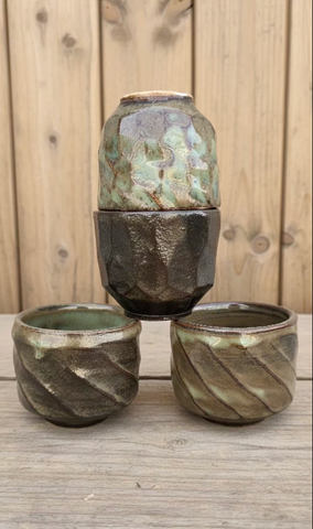 Set of three ceramic pots with textured surfaces on a wooden surface.