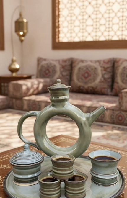Decorative ceramic teapot and cups on a tray with a patterned sofa in the background