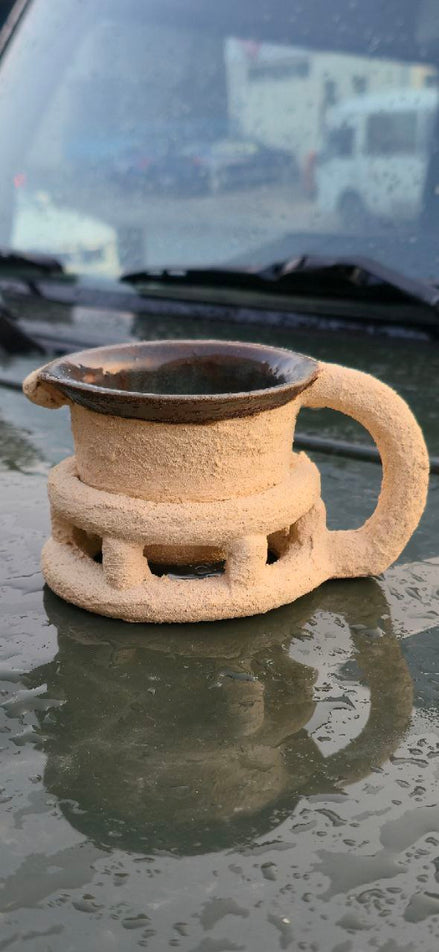 Ceramic mug with handle on a reflective surface, possibly car windshield