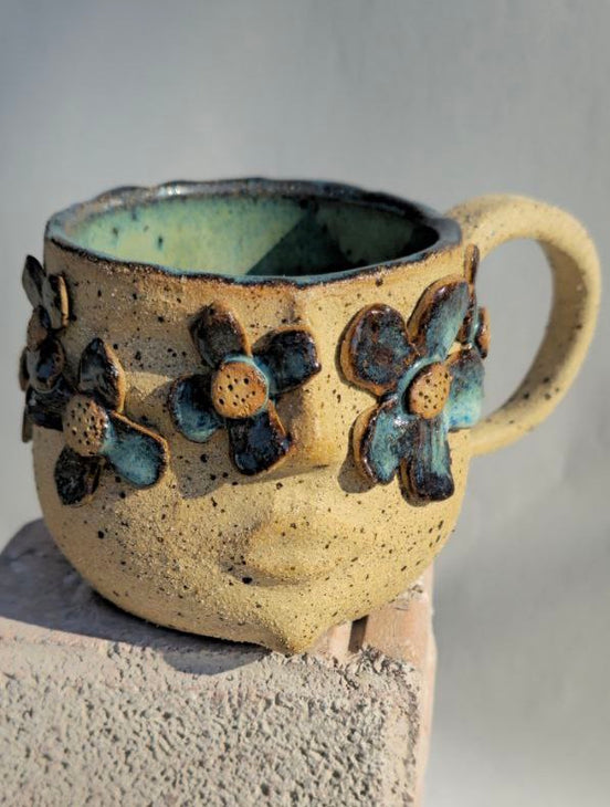 Ceramic mug with floral designs on a neutral background