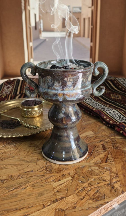Decorative urn with smoking incense on a wooden table